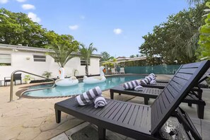 Ein Poolbereich mit Liegestühlen, Schwane als Pooltiere und blauem Himmel.