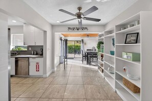 Eine moderne Küche mit weißen Schränken, ein Essbereich mit Tisch und Stühlen sowie ein Deckenventilator.