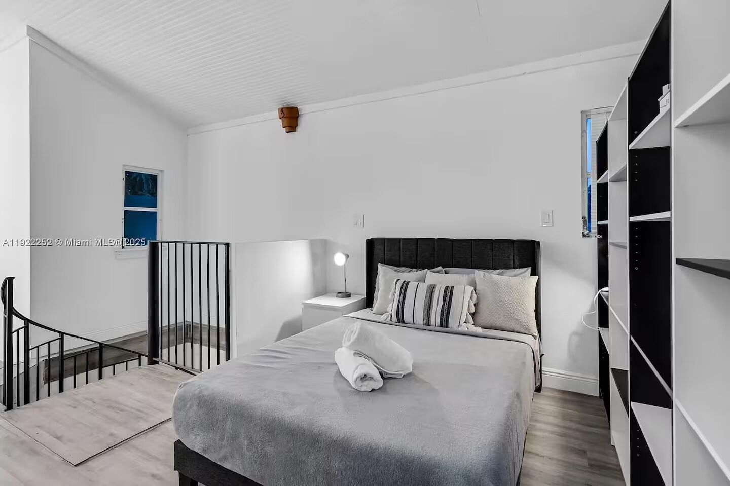 Een moderne slaapkamer met een bed, nachtkastje, lamp en uitzicht.