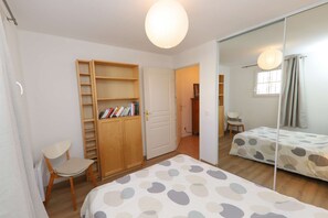 Ein Schlafzimmer mit einem Bett, einem Sessel, einem Kleiderschrank und einem Spiegel.