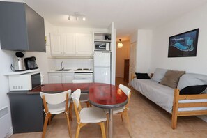 Ein kompakter Wohnbereich mit Küchenzeile, einem Essbereich mit Tisch und Stühlen, einer Couch und einem gerahmten Bild an der Wand.
