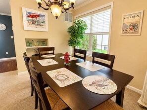 A dining room with a dark wooden table, six chairs, and placemats with animal prints.