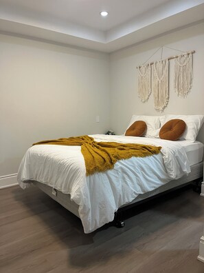 Ein Schlafzimmer mit einem Bett, einer Wanddeko aus Makramee und einem Holzboden.