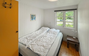 A small room with a bed, a desk, a window with a view, and a door. - 4 bedroom gorgeous home in Væggerløse (Væggerløse)
