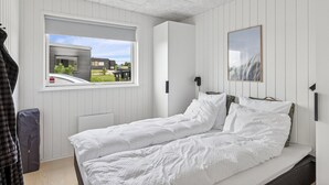 Une chambre à coucher avec un lit, une fenêtre, une porte et un tableau encadré au mur.
