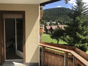 Ein Balkon mit Blick auf einen bewaldeten Berg und ein Gebäude mit rotem Dach.
