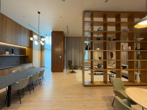 A modern interior with a dining area, a wooden bookshelf, and a seating area with a sofa and a chair.