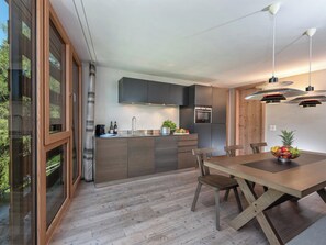 Eine moderne Küche mit einer zentralen Kochinsel, Edelstahlgeräten und einem Essbereich mit Holztisch und Stühlen.