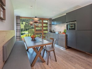 Una cocina moderna con horno integrado y comedor con mesa y banco de madera.