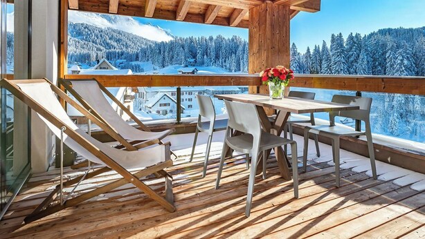A wooden deck with a table and chairs, overlooking a snowy mountain landscape. - Turrabuel Appartement/Fewo Turrabuel 4-Zimmer Deluxe Family by Interhome (Parpan)