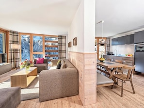 Ein modernes Wohnzimmer mit einer Couch, einem Couchtisch und Blick auf verschneite Bäume durch große Fenster.