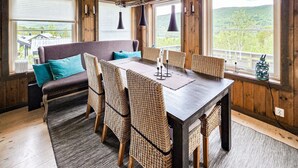 A dining area with a wooden table, wicker chairs, and a sofa with teal cushions. - Amazing home in Hovet with sauna (Hovet)