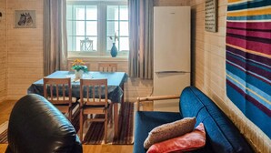 A cozy room with a dining table, chairs, a sofa, a colorful rug, and a window with curtains.