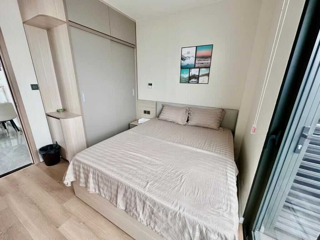 Un dormitorio con cama, armario, una mesita y un cuadro colgado en la pared.