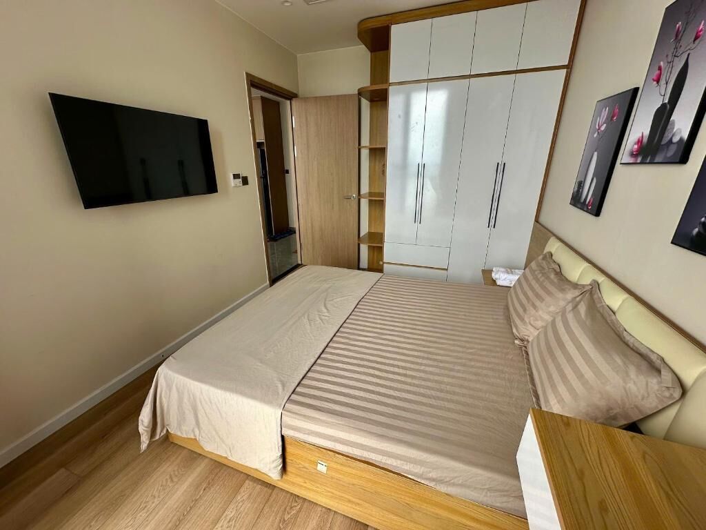 Un dormitorio con cama, televisor, armario y una obra de arte colgada en la pared.