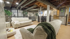 Un espacio de sala acogedor con un sofá, una silla y una mesita con una manta.