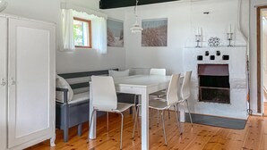 Un coin repas avec une table blanche, quatre chaises, un banc et une cheminée.