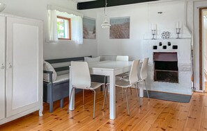 Ein Essbereich mit einem weißen Tisch, vier Stühlen, einer Bank und einem Kamin.