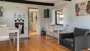 Un salon moderne avec un canapé en cuir noir, des meubles blancs et un plancher en bois.