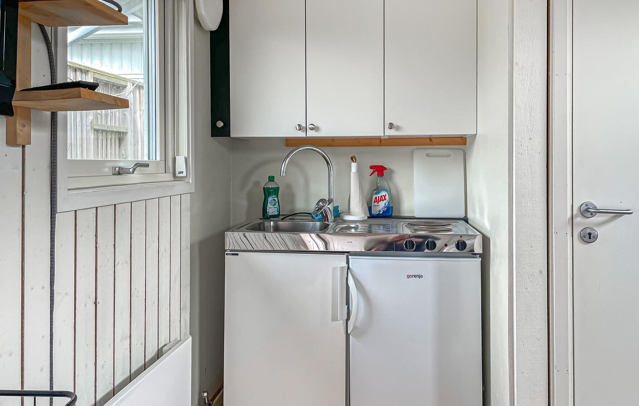 A compact kitchenette with a built-in stove, a sink, and a window above the counter.