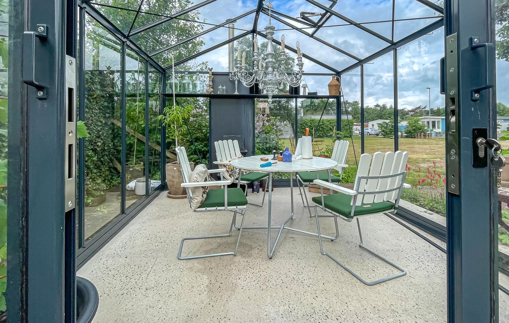 A conservatory with a glass ceiling, a round table with chairs, and a chandelier.