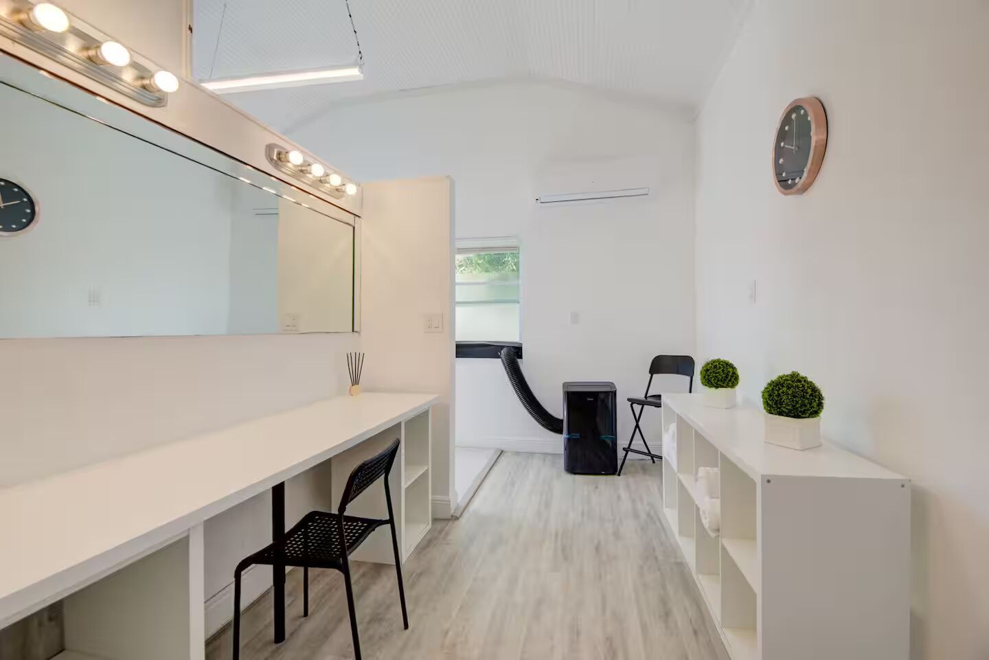 A modern, well-lit room with a vanity, mirror, and seating area.