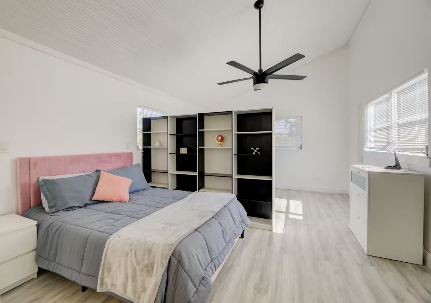 Una camera da letto con un letto, una scrivania, un armadio e una ventola a soffitto.