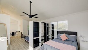 A bedroom with a bed, a ceiling fan, a window, and built-in shelving. - Cozy 1-bedroom house in pleasant Pompano Beach with AC (Pompano Beach)