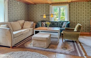 A cozy living room with patterned wallpaper, a sofa, a coffee table, and a chair. - Gorgeous home in Aneby with WiFi (Aneby)