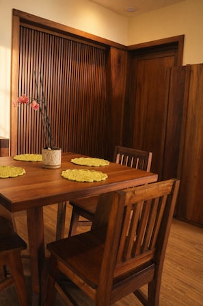Une table à manger en bois, accompagnée de quatre chaises, un vase rempli de fleurs roses et un mur recouvert de panneaux en bois.