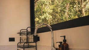 A kitchen with a double sink, a faucet, a soap dispenser, and a window with a view of trees.