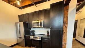 Een moderne keuken met donkere kastjes, roestvrijstalen apparatuur en een houten vloer.