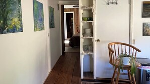 A hallway with wooden flooring, a dining area with a chair and table, and a door with shelves. - Durango Oasis: Trout Ponds, Wildlife & Trails (Durango)