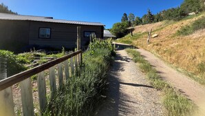 A rural setting with a dirt path leading to a wooden house with a metal roof. - Durango Oasis: Trout Ponds, Wildlife & Trails (Durango)