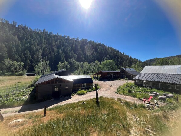 A rural property with multiple buildings, including a barn and cabins, surrounded by a forested hillside. - Durango Oasis: Trout Ponds, Wildlife & Trails (Durango)