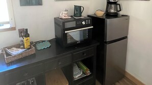 A compact kitchenette with a microwave, coffee maker, and refrigerator. There are wall art pieces and a small window. - Durango Oasis: Trout Ponds, Wildlife & Trails (Durango)