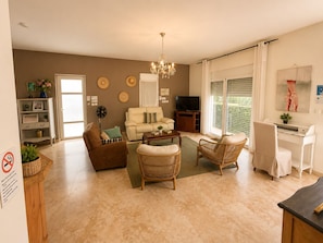A living room with a sofa, chairs, a coffee table, a TV, and a desk with a computer. - L'Éden de Bois Noir – Villa 1 with Heated Pool (Saint Joseph)