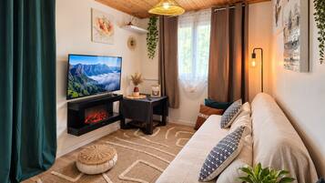 Ein gemütliches Wohnzimmer mit Kamin, einer Couch, einem Fernseher und einer Pendelleuchte.