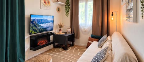 Un salón acogedor con chimenea, un sofá, un televisor y una lámpara colgante.
