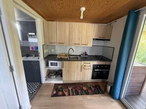 Une cuisine de taille réduite, dotée de meubles en bois, d’un four à micro-ondes, d’une cuisinière et d’un évier.