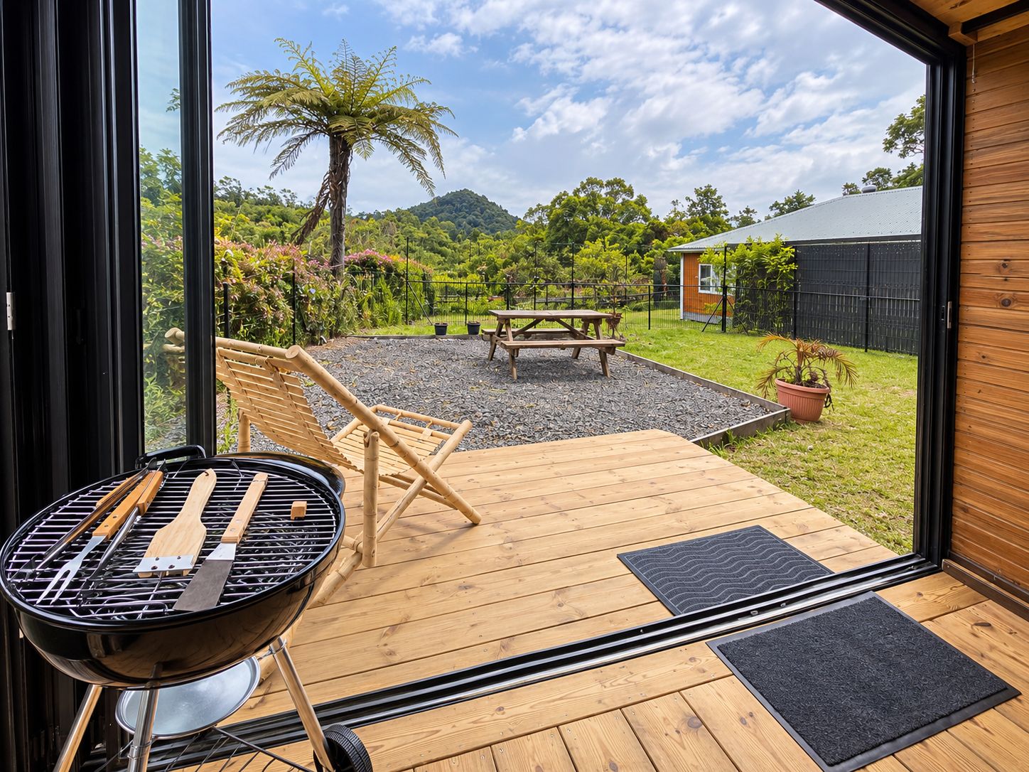 Una terraza de madera con una parrilla, un banco y una mesa de picnic.