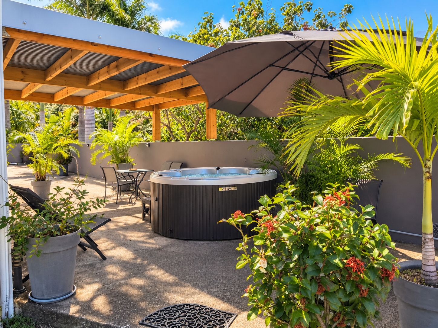 A hot tub under a pergola, surrounded by potted plants and a patio table.
