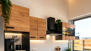 Eine moderne Küche mit Holzausstattung, einem eingebauten Ofen und einer Kaffeoase.
