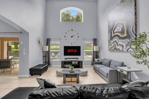 Ein modernes Wohnzimmer mit großem Fernseher, einer Couch, einem Couchtisch und einem Gemälde an der Wand.
