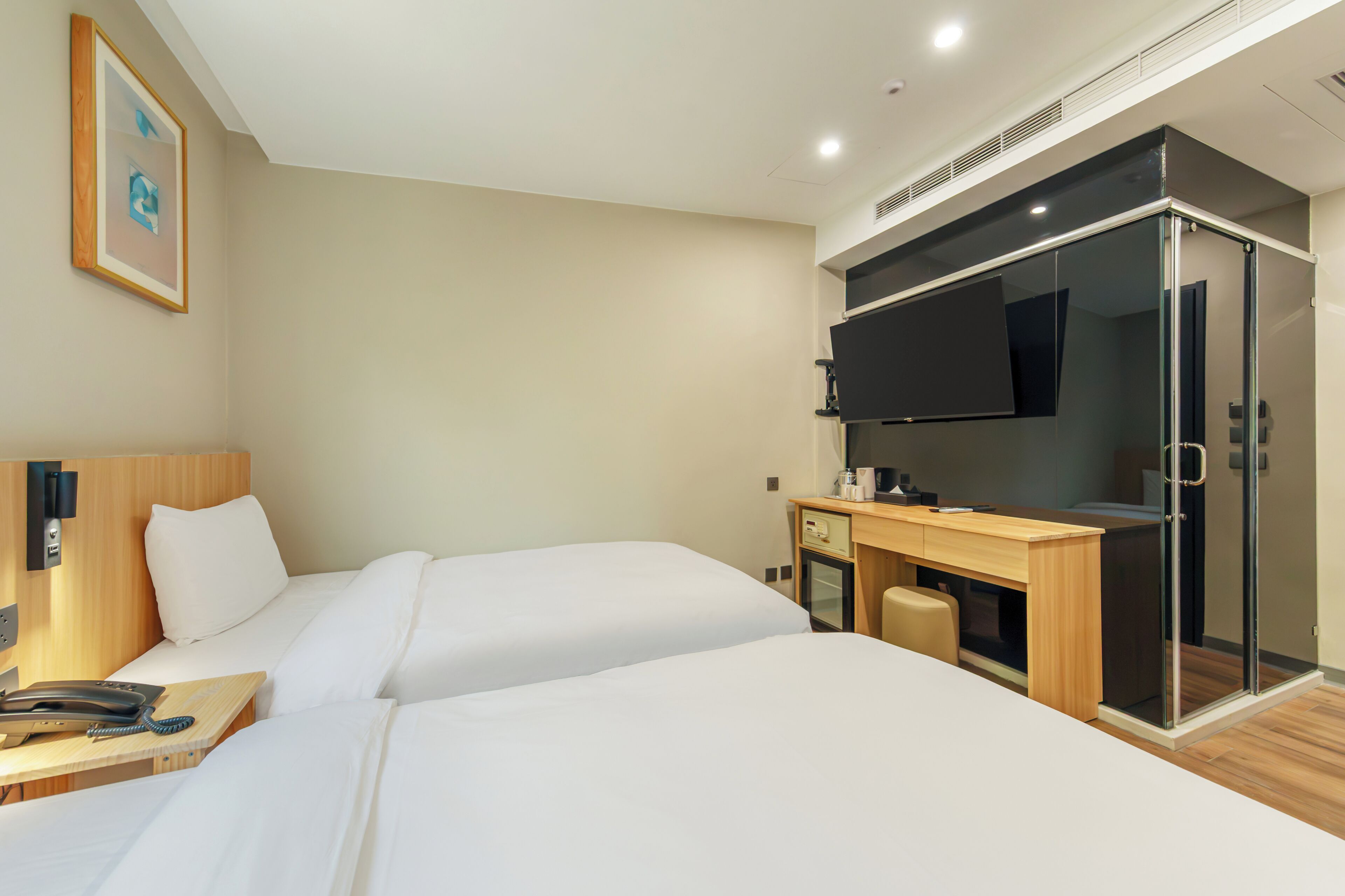 Een hotelkamer met twee bedden, een bureau met telefoon en een televisie.