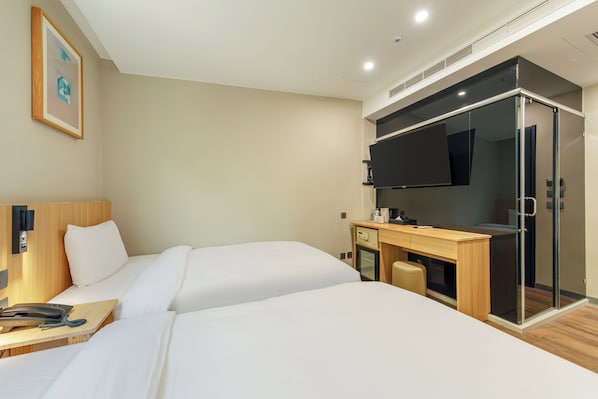 Habitación de hotel con dos camas, un escritorio con teléfono y una televisión.