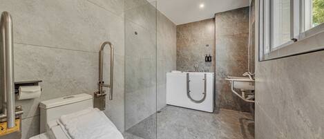Un baño moderno con inodoro, bidé y zona de ducha con mampara de vidrio.