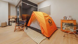 A room with a tent set up, a chair, a small table with a kettle, and a radiator. - WHIYORI INN (Kaohsiung)