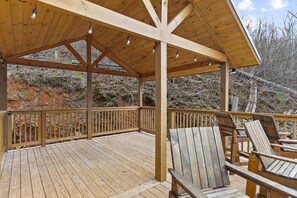 Eine Holzterrasse mit überdachtem Bereich, Holzwertlauf und zwei Holzstühlen.