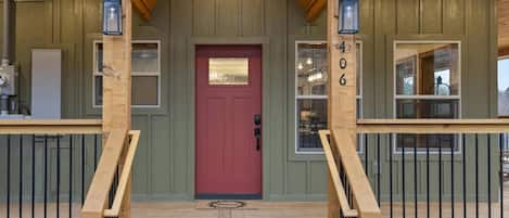 A wooden cabin with a red door, a number '406' on the wall, and a 'welcome' mat at the entrance.